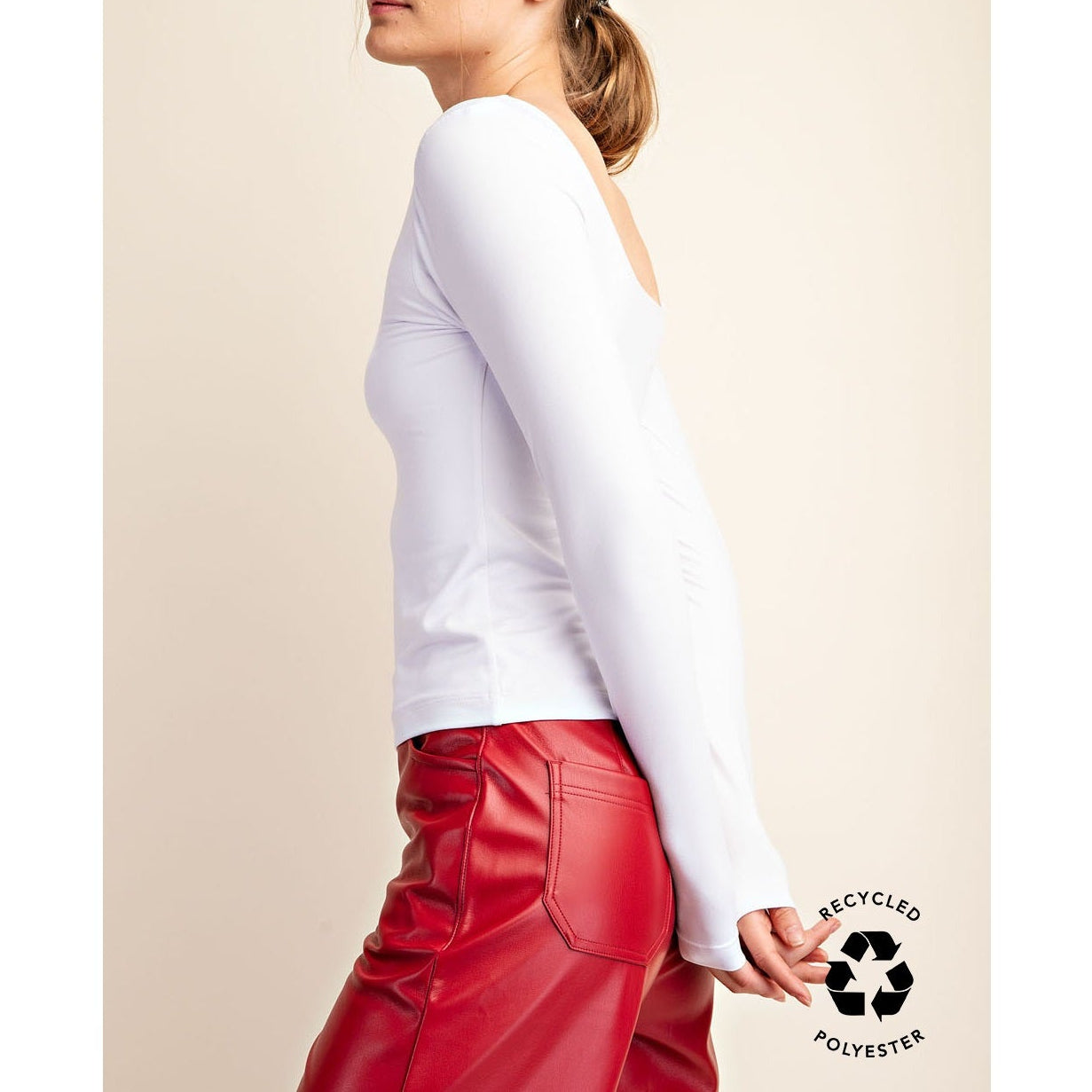 Woman wearing a white long-sleeve top and red pants on a beige background with a 'recycled polyester' label.