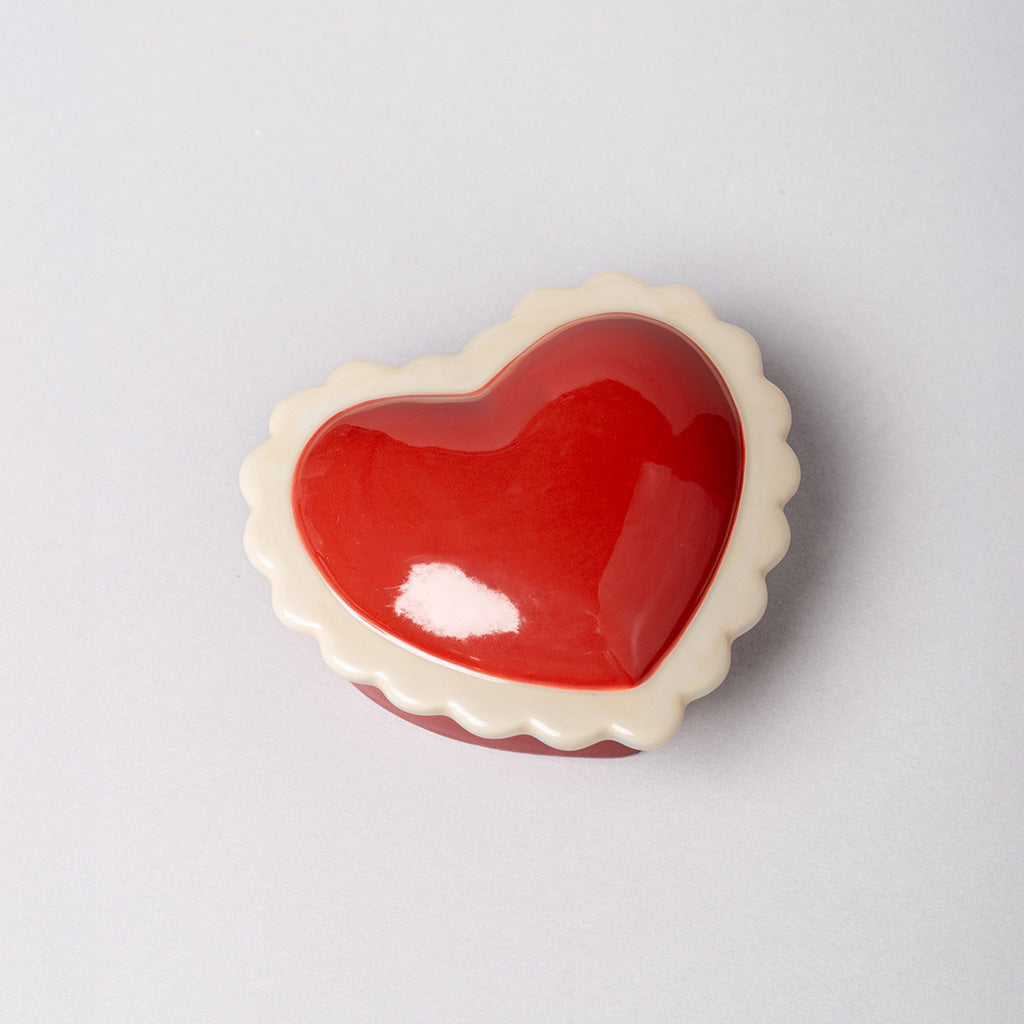 Heart-shaped red ceramic dish on a light gray background