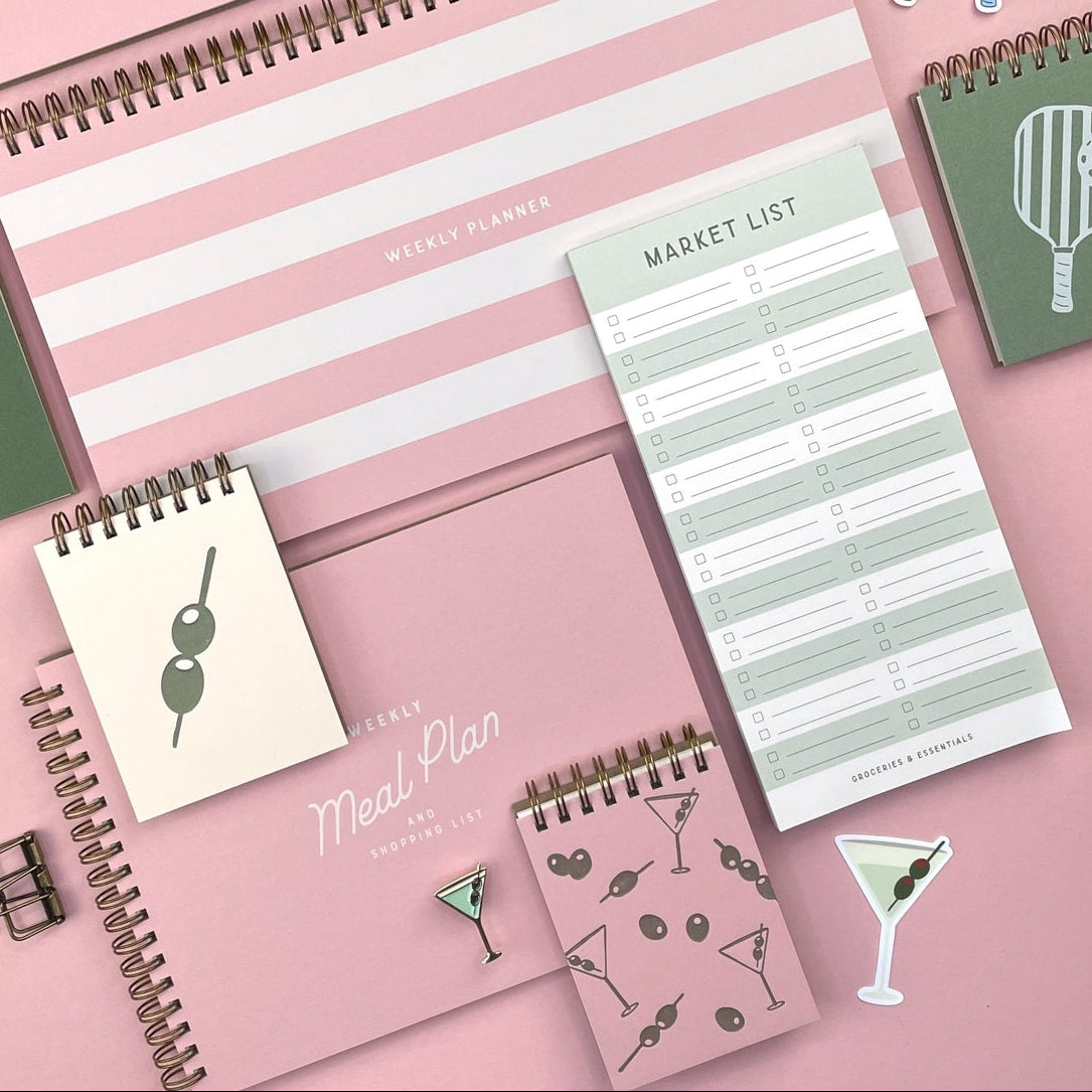 Collection of planners and stationery items on a pink background