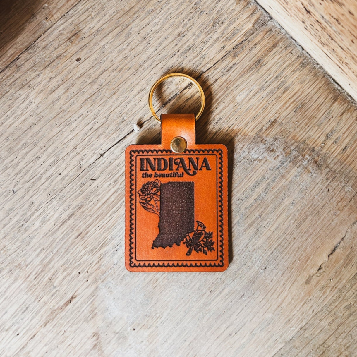 Orange leather keychain with 'Indiana' text and map on a wooden surface