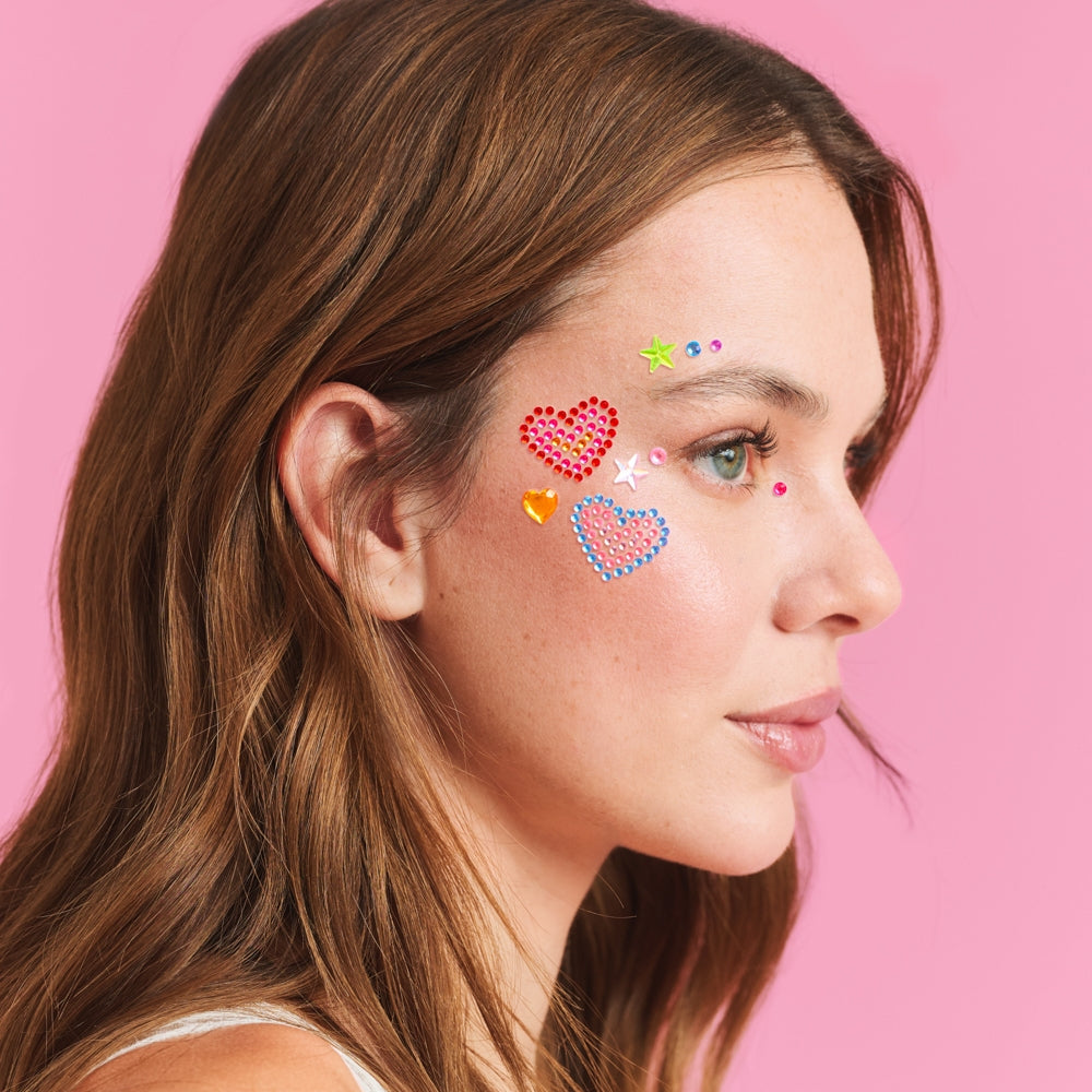 Woman with colorful heart-shaped stickers on her face against a pink background