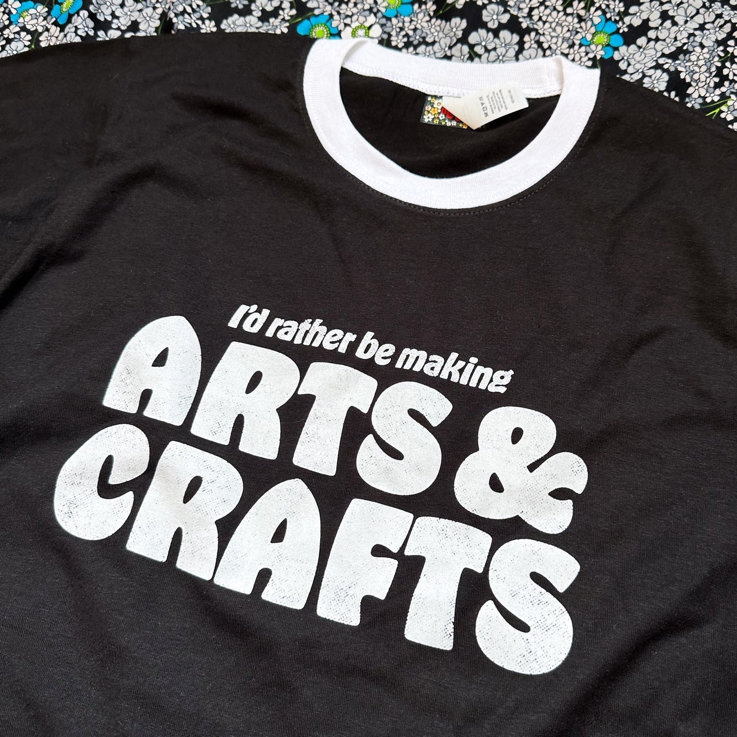 Black t-shirt with 'I'd rather be making ARTS & CRAFTS' text on a textured surface.