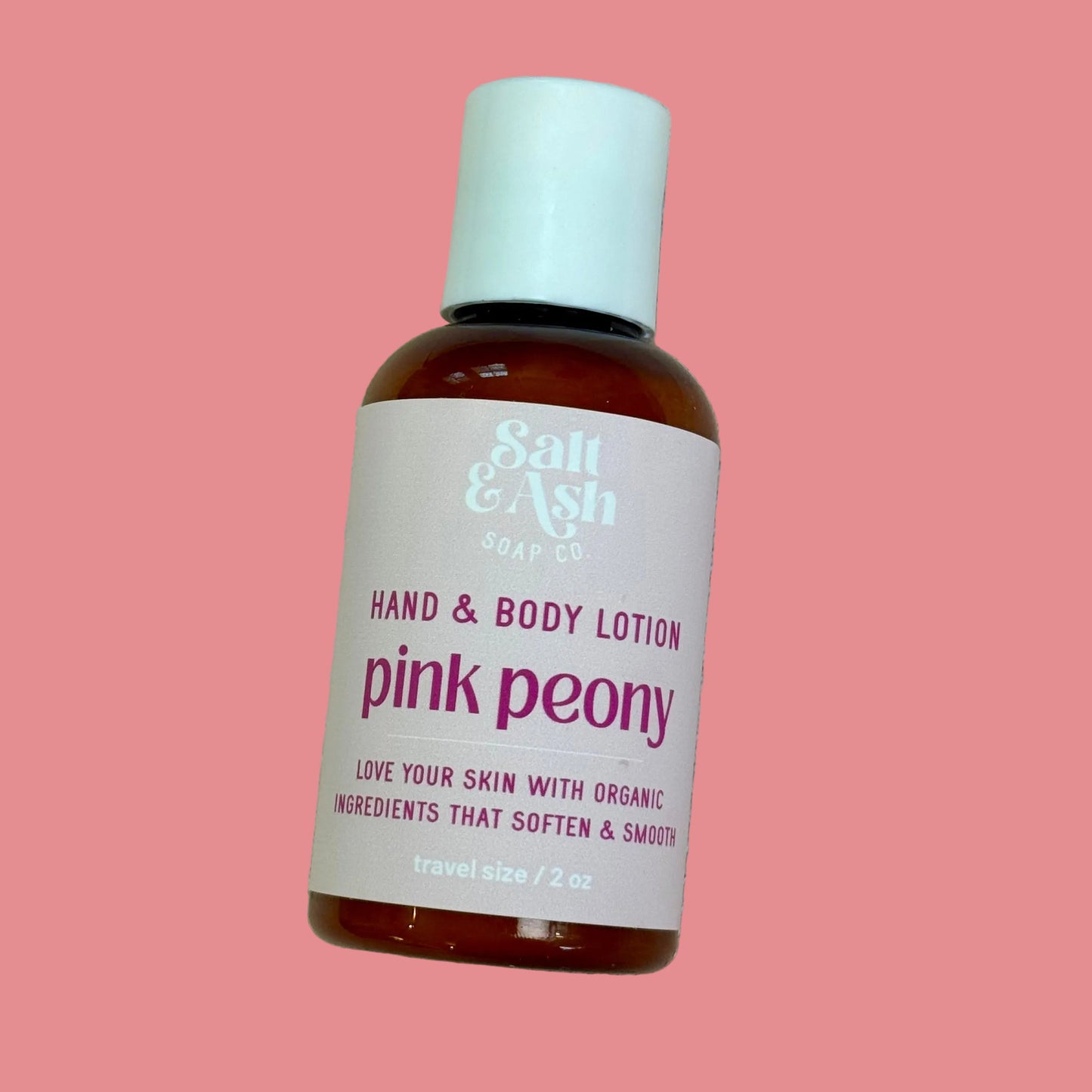 Bottle of Salt & Ash Soap Co. pink peony hand and body lotion on a pink background