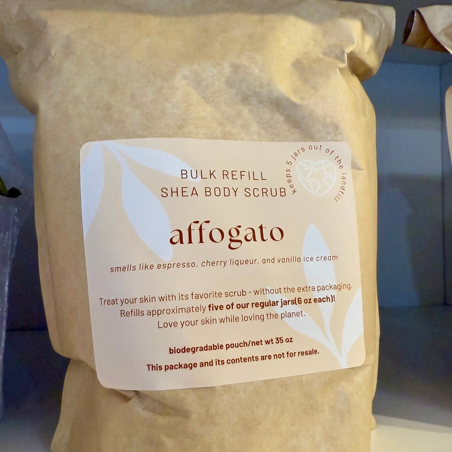 Shea body scrub refill bag labeled 'affogato' with a visible label on a blurred background.