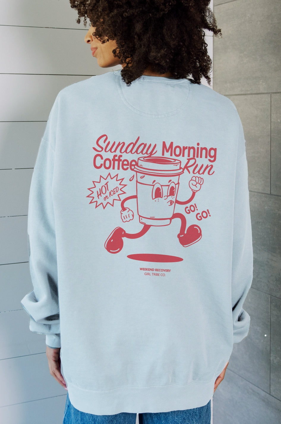 Person wearing a light blue sweatshirt with a red graphic and text on the back.