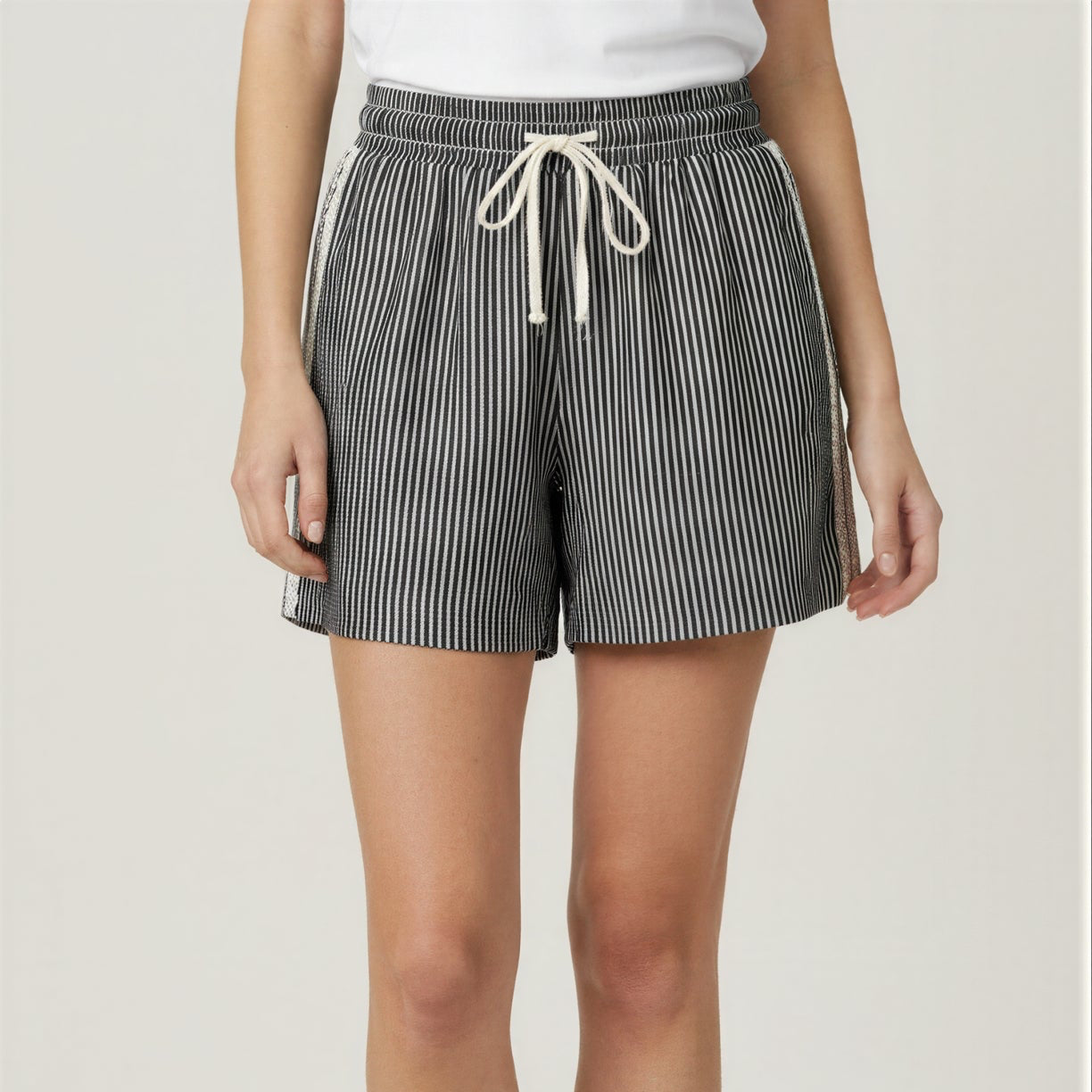 Person wearing black and white striped shorts on a plain background