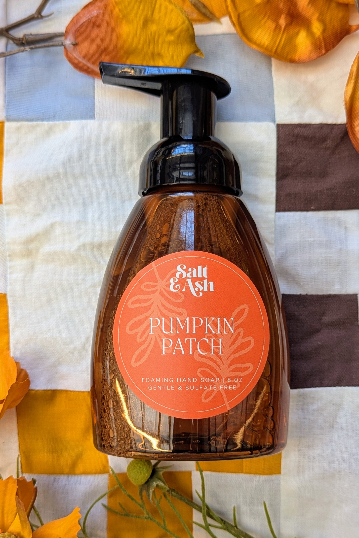 Bottle of 'Pumpkin Patch' hand soap with a pump dispenser on a checkered fabric background.